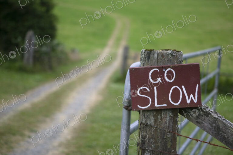 Go slow sign on wooden countryside gate.