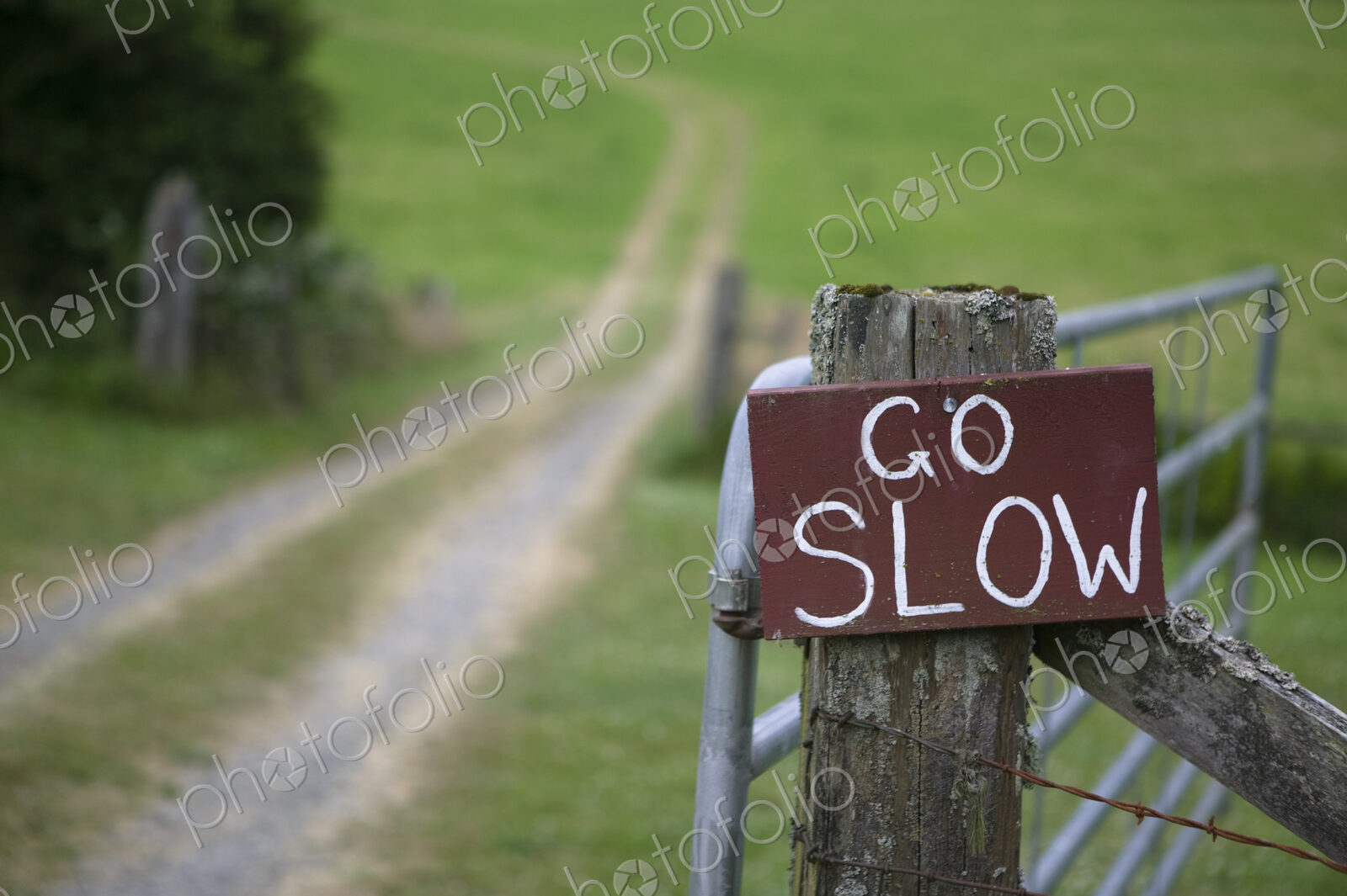 Go slow sign on wooden countryside gate.
