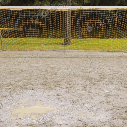 Goal net on muddy soccer field.
