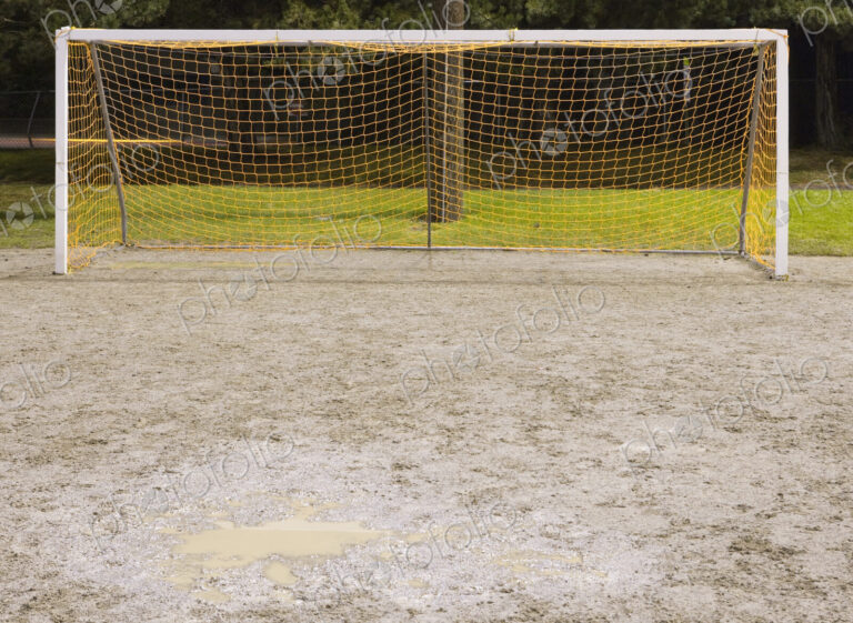 Goal net on muddy soccer field.
