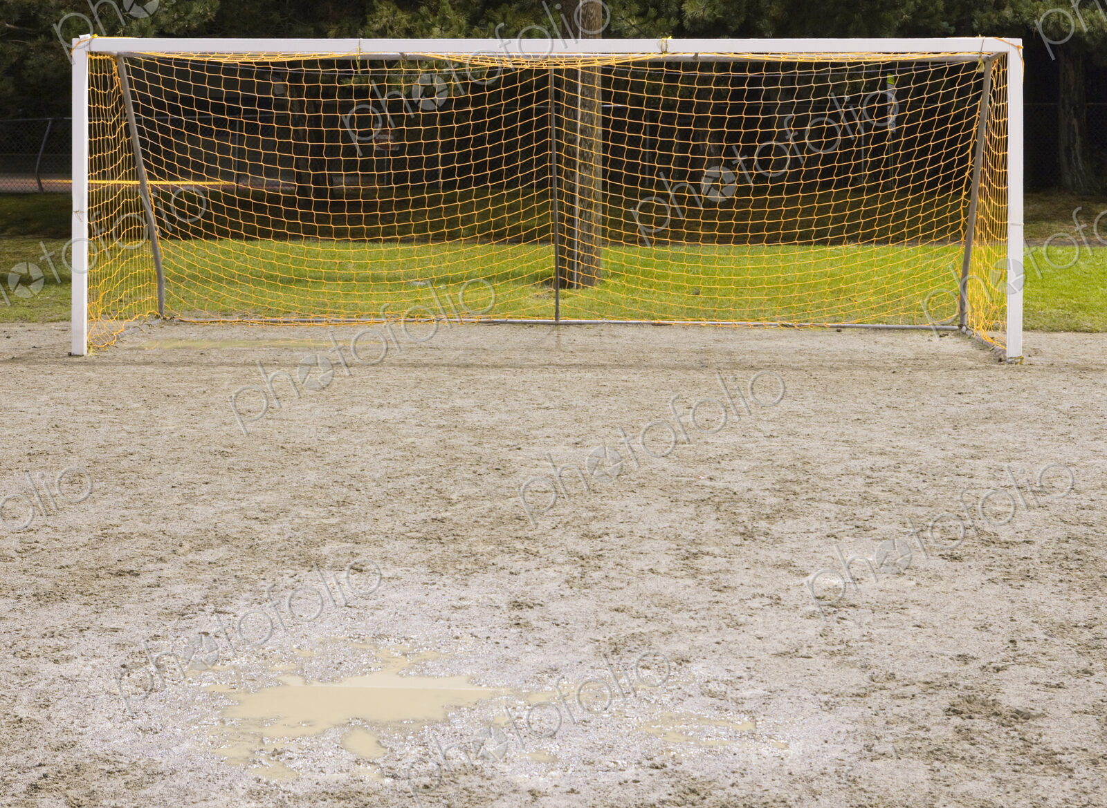 Goal net on muddy soccer field.