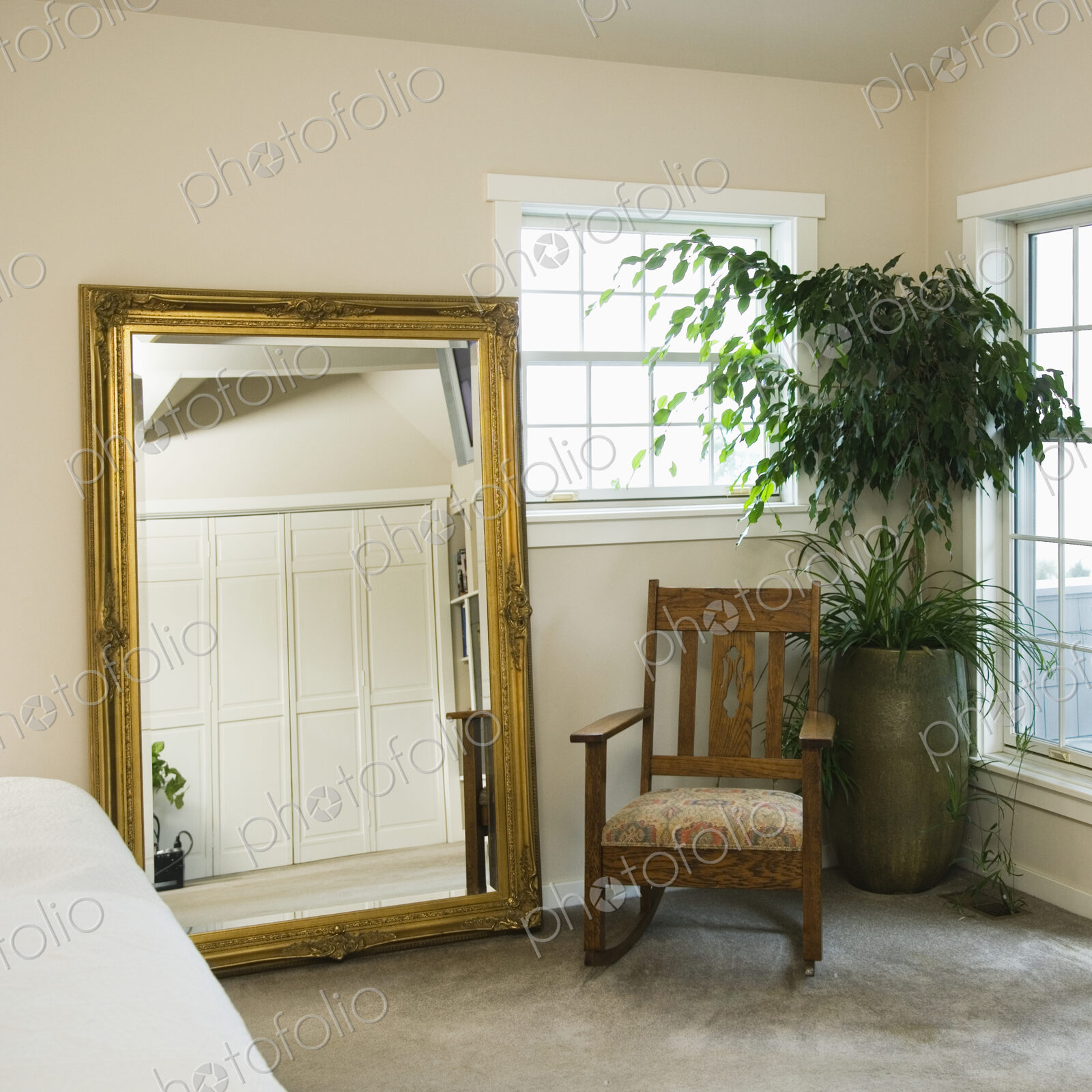 Gold mirrror and rocking chair with potted plant in bedroom.