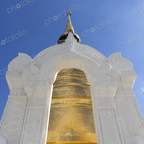 Gold painted chedi at Wat Suan Dok, white stone archway and tall tapered tower. Gold painted chedi at Wat Suan Dok, white stone archway and tall tapered tower.