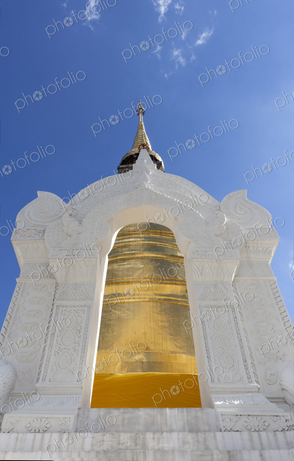 Gold painted chedi at Wat Suan Dok, white stone archway and tall tapered tower.