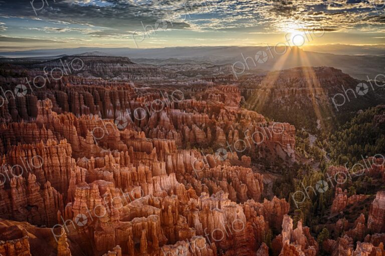 Golden sunbeams pierce the horizon at Bryce Canyon, casting dramatic light over the…