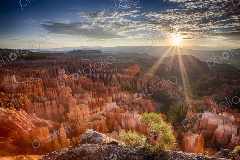 Golden sunbeams pierce the horizon at Bryce Canyon, casting dramatic light over the…