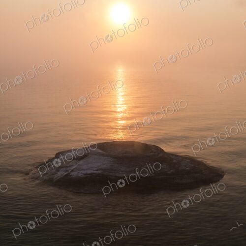 Golden sunrise over Yellowstone Lake with Fishing Cone hot spring emerging from the… Golden sunrise over Yellowstone Lake with Fishing Cone hot spring emerging from the…
