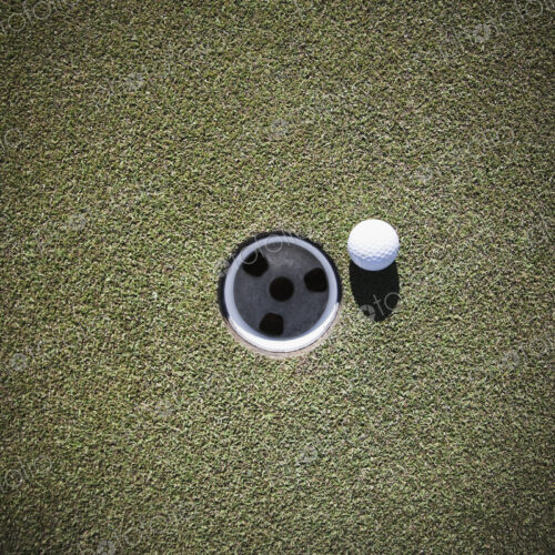 Golf Ball Next to a Putting Cup