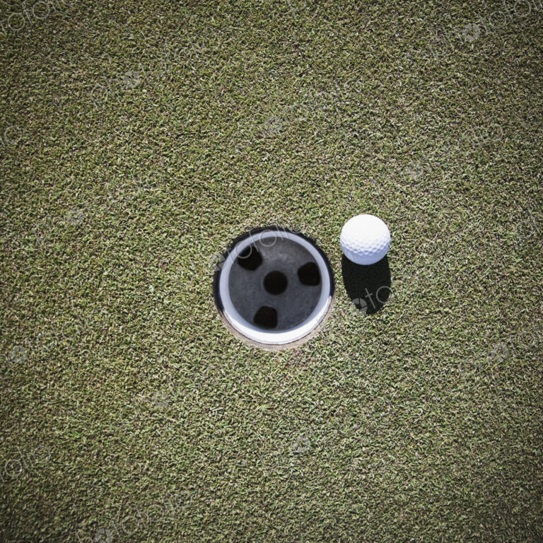 Golf Ball Next to a Putting Cup
