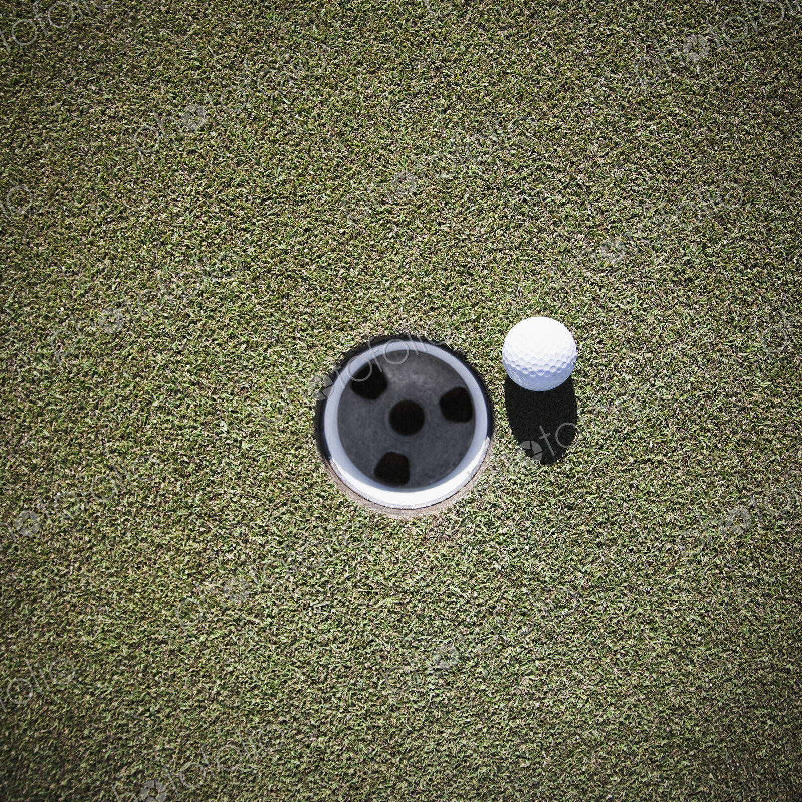 Golf Ball Next to a Putting Cup