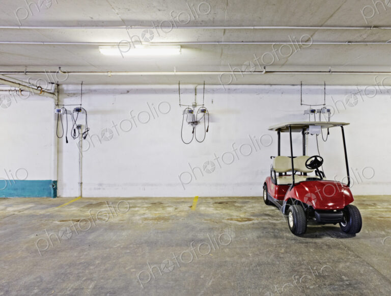 Golf buggy in a parking lot.
