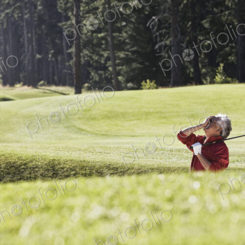Golfer reacting with frustration at a missed shot from a bunker near the green on a…