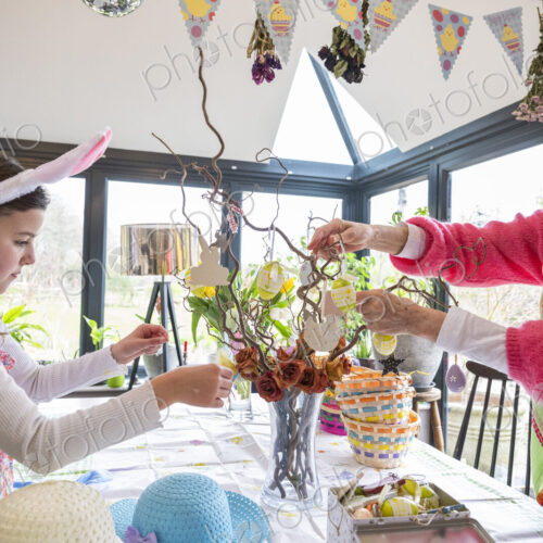 Grandmother and grandchild arranging Easter ornaments on kitchen table.