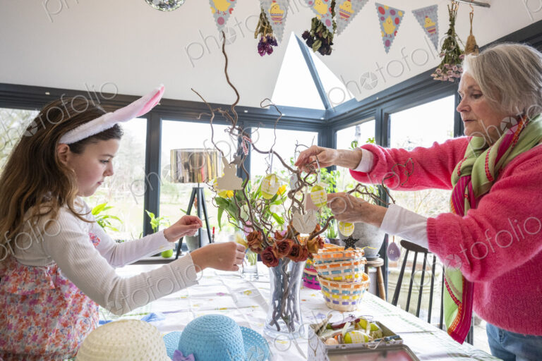 Grandmother and grandchild arranging Easter ornaments on kitchen table.