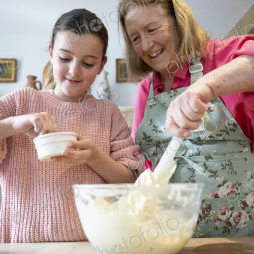 Grandmother and granddaughter baking together in kitchen.