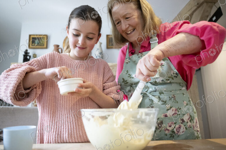 Grandmother and granddaughter baking together in kitchen.