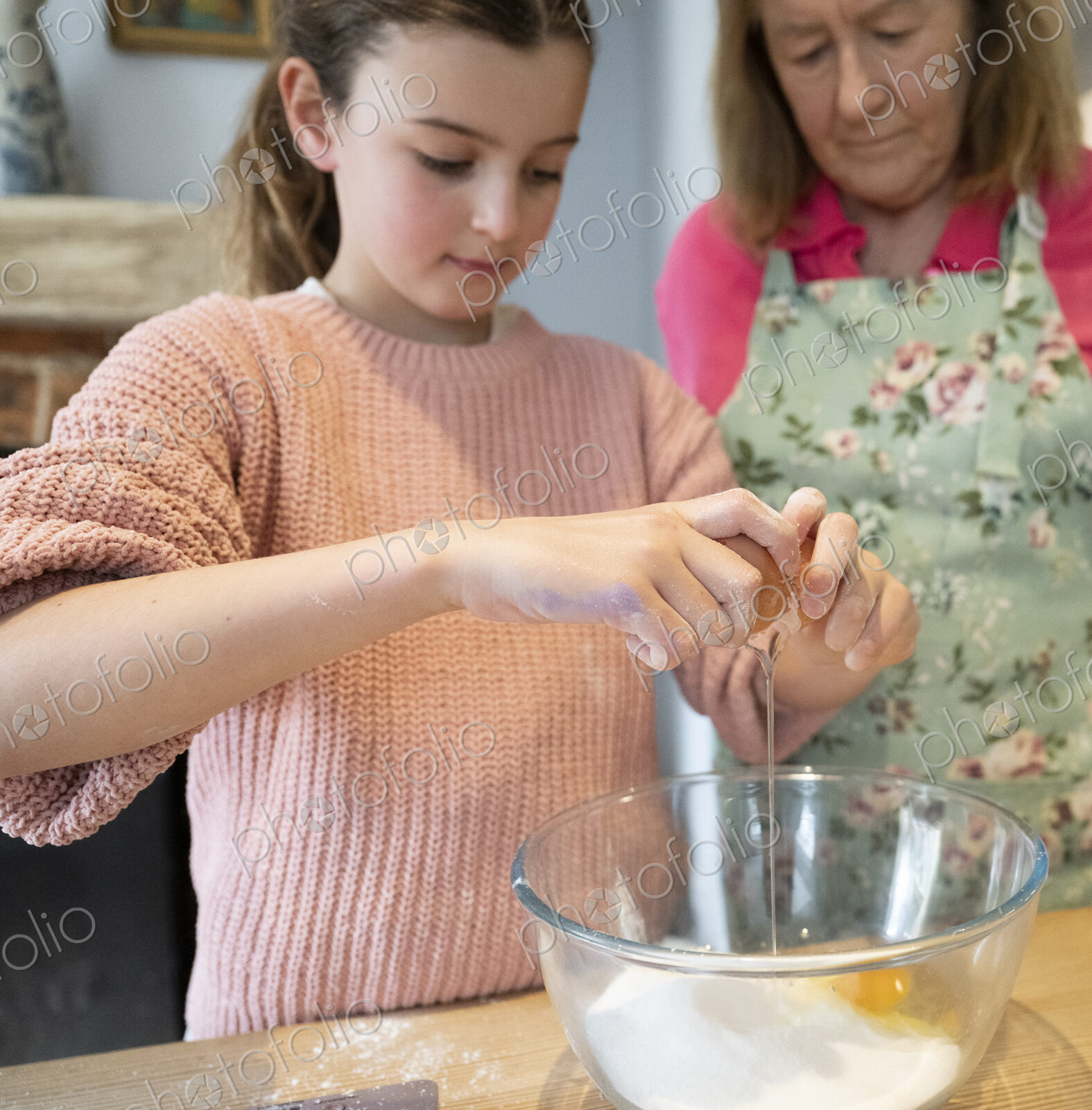 Grandmother and granddaughter baking together in kitchen.