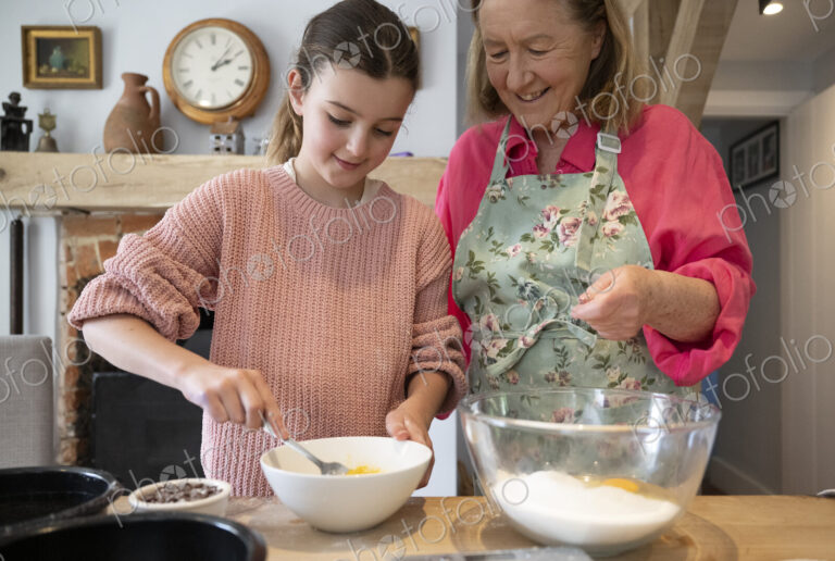 Grandmother and granddaughter baking together in kitchen.