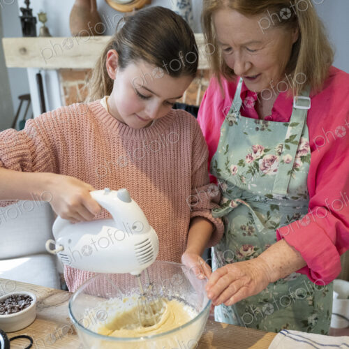 Grandmother and granddaughter baking together in kitchen.