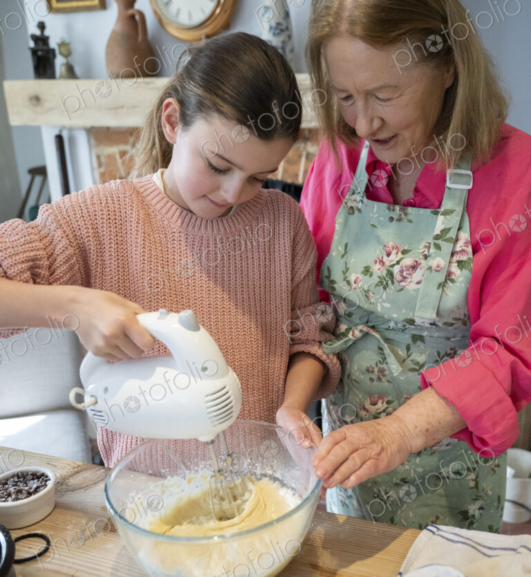 Grandmother and granddaughter baking together in kitchen.