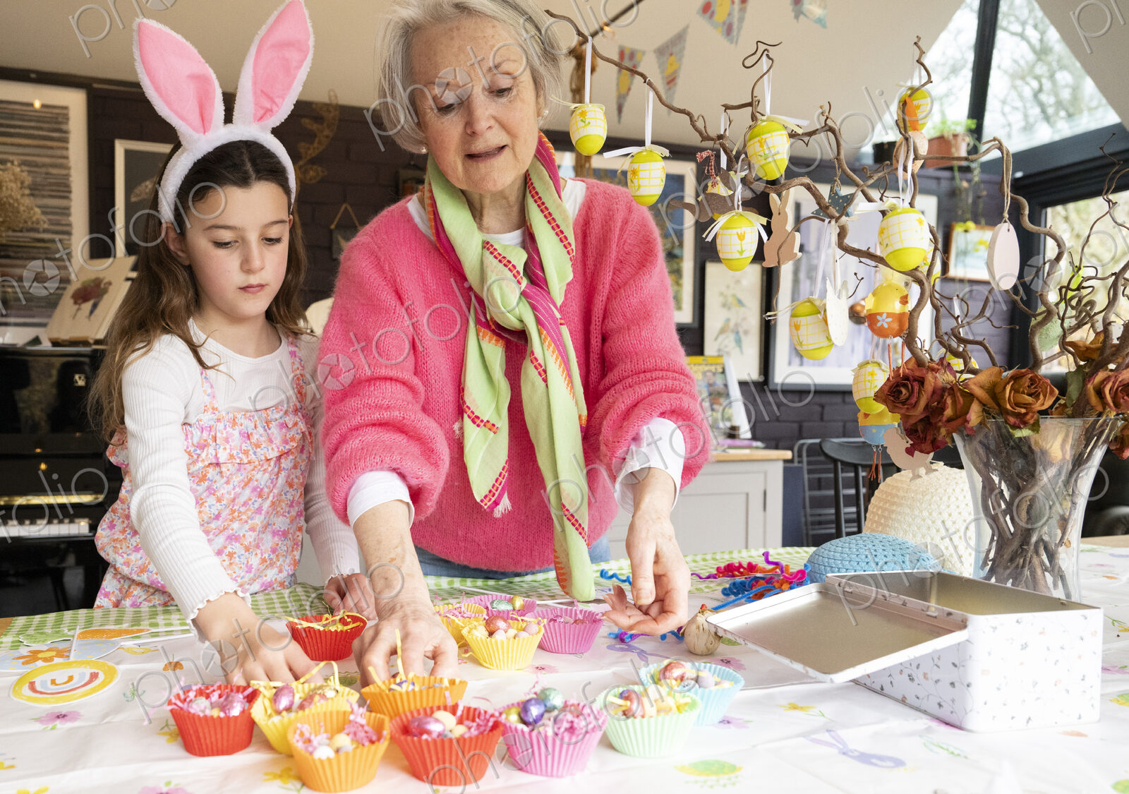 Grandmother and granddaughter making Easter cakes together in kitchen.