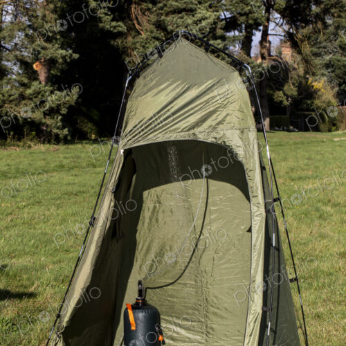 Green shower tent pitched on a meadow.