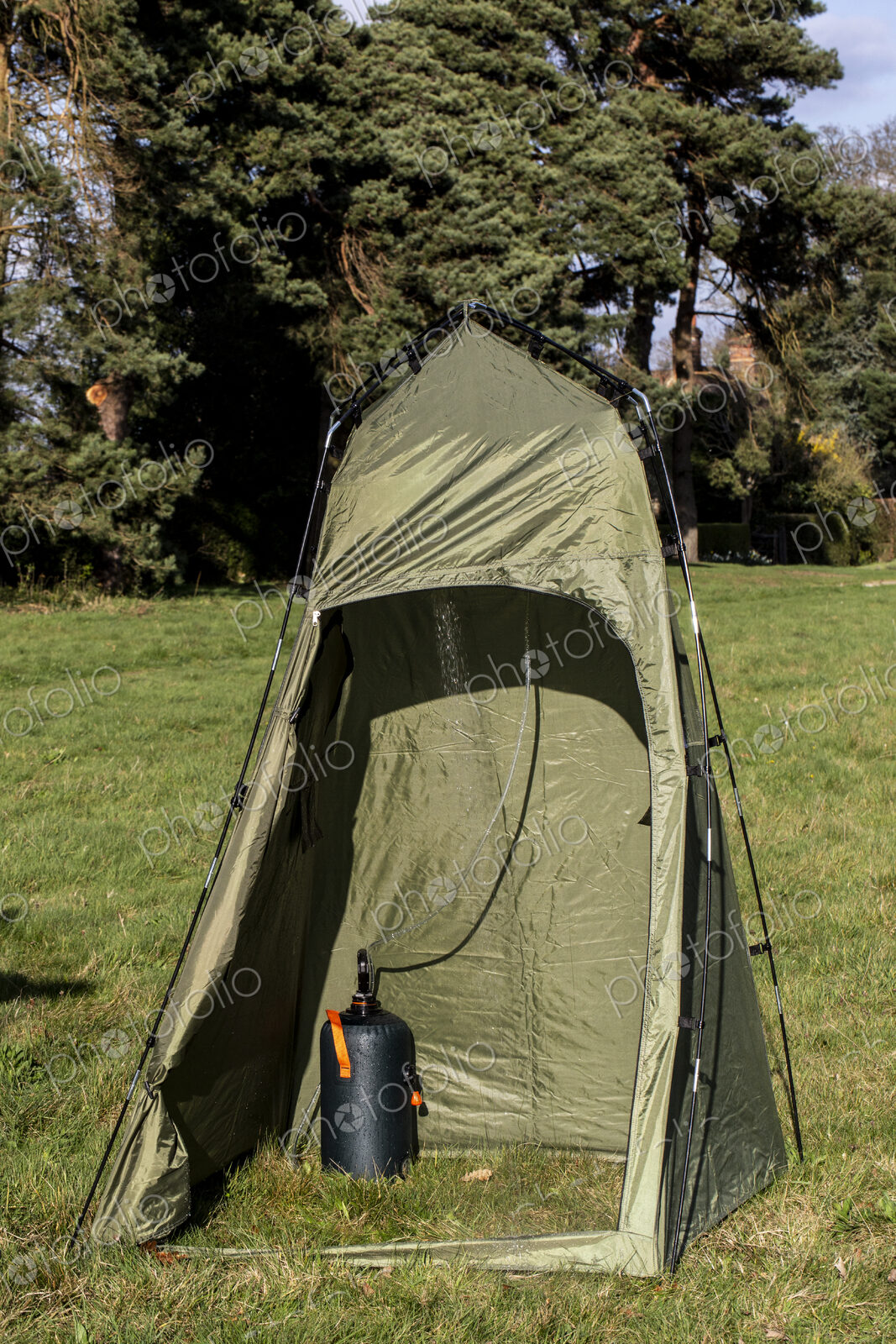 Green shower tent pitched on a meadow.