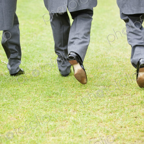 Groom and two best man in black shoes, grey trousers and morning coats walking along a… Groom and two best man in black shoes, grey trousers and morning coats walking along a…