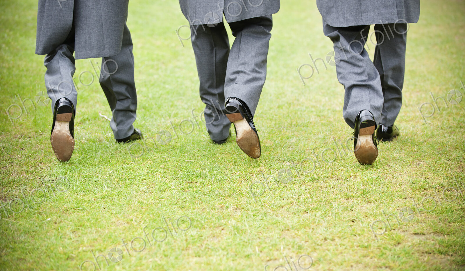 Groom and two best man in black shoes, grey trousers and morning coats walking along a…