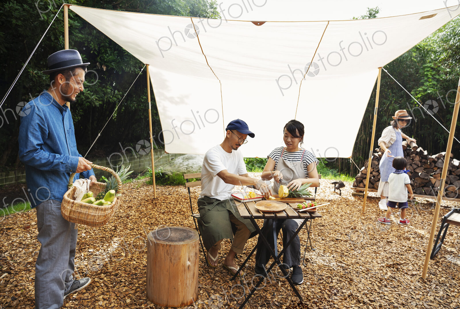 Group of Japanese men and women and boy gathered around a table under a canopy,…