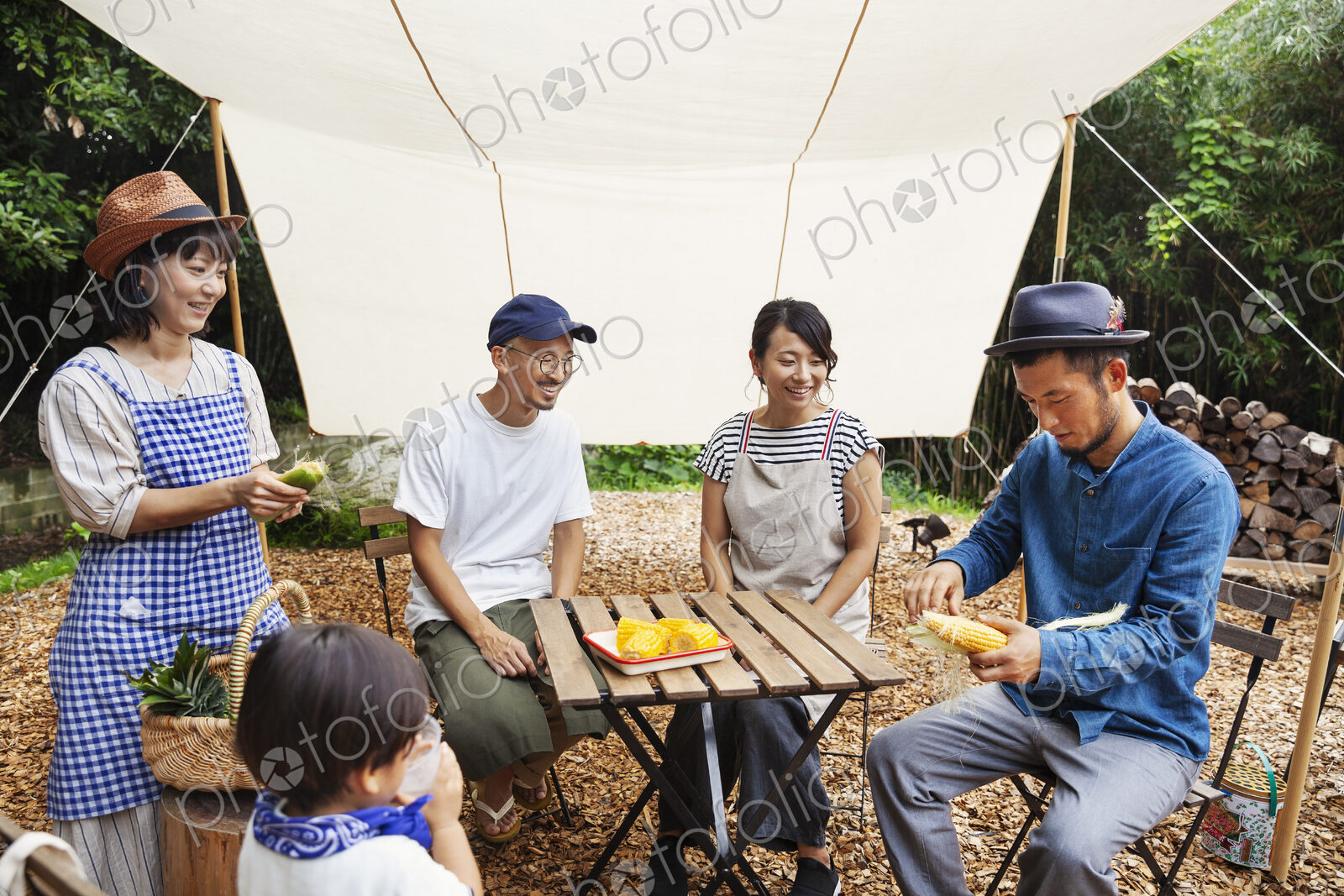 Group of Japanese men and women and boy gathered around a table under a canopy,…