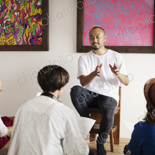 Group of Japanese men and women sitting in art gallery, holding a discussion.