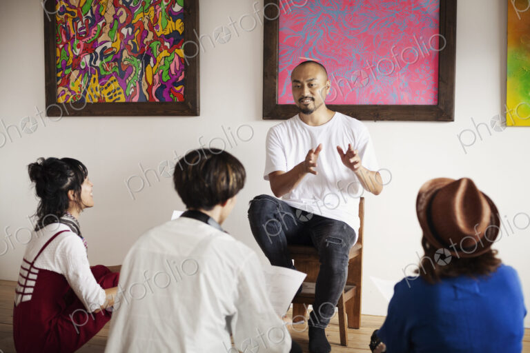 Group of Japanese men and women sitting in art gallery, holding a discussion.