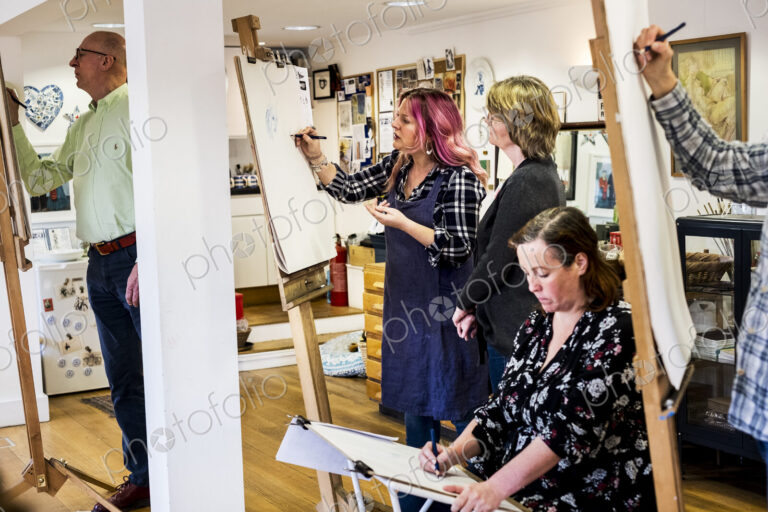 Group of artists standing and sitting at easels, drawing.