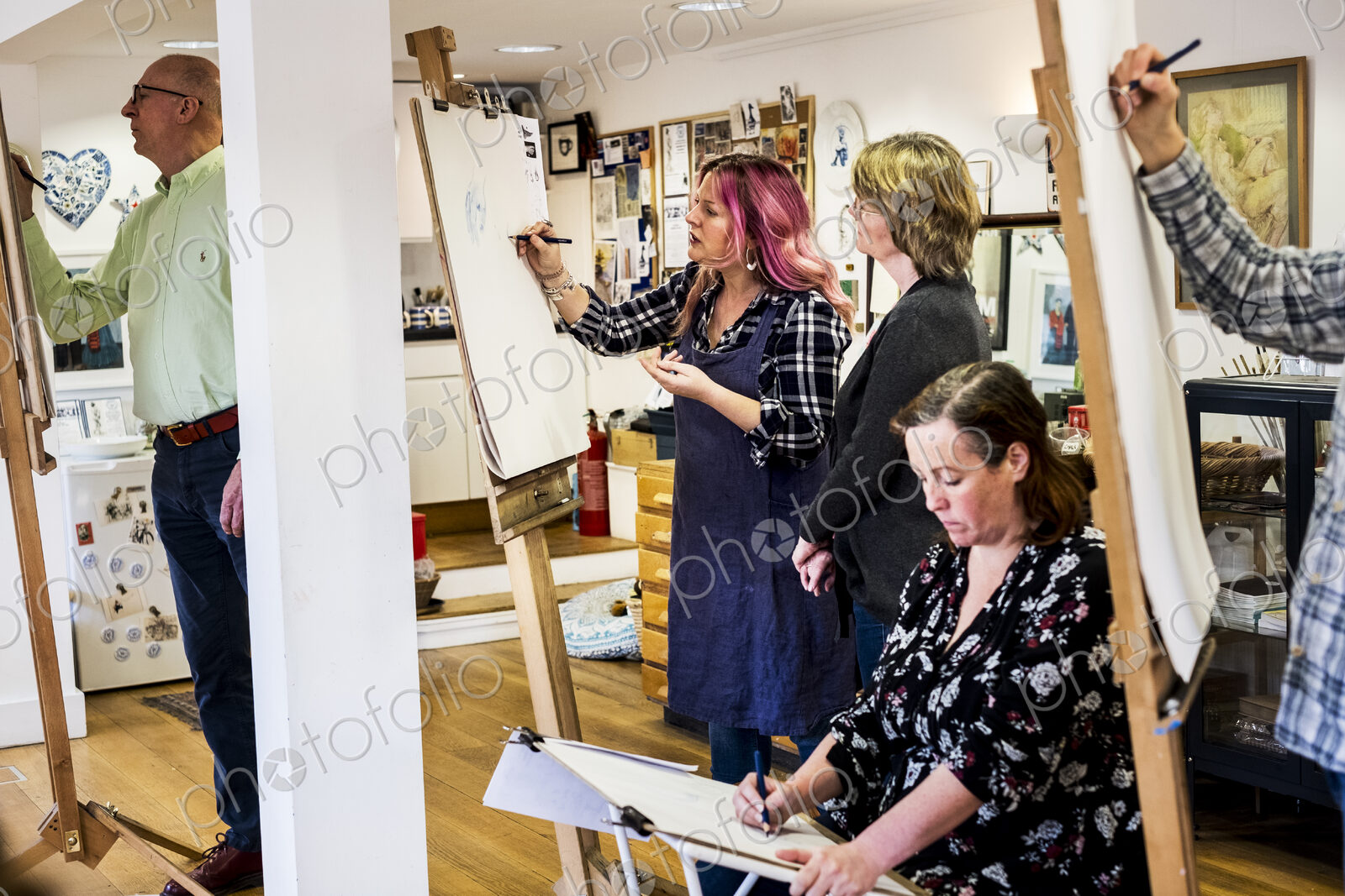 Group of artists standing and sitting at easels, drawing.