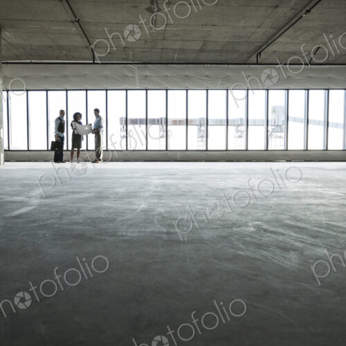 Group of business people looking at a new empty raw office space.