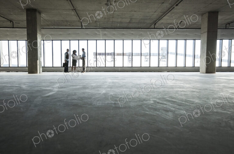 Group of business people looking at a new empty raw office space.