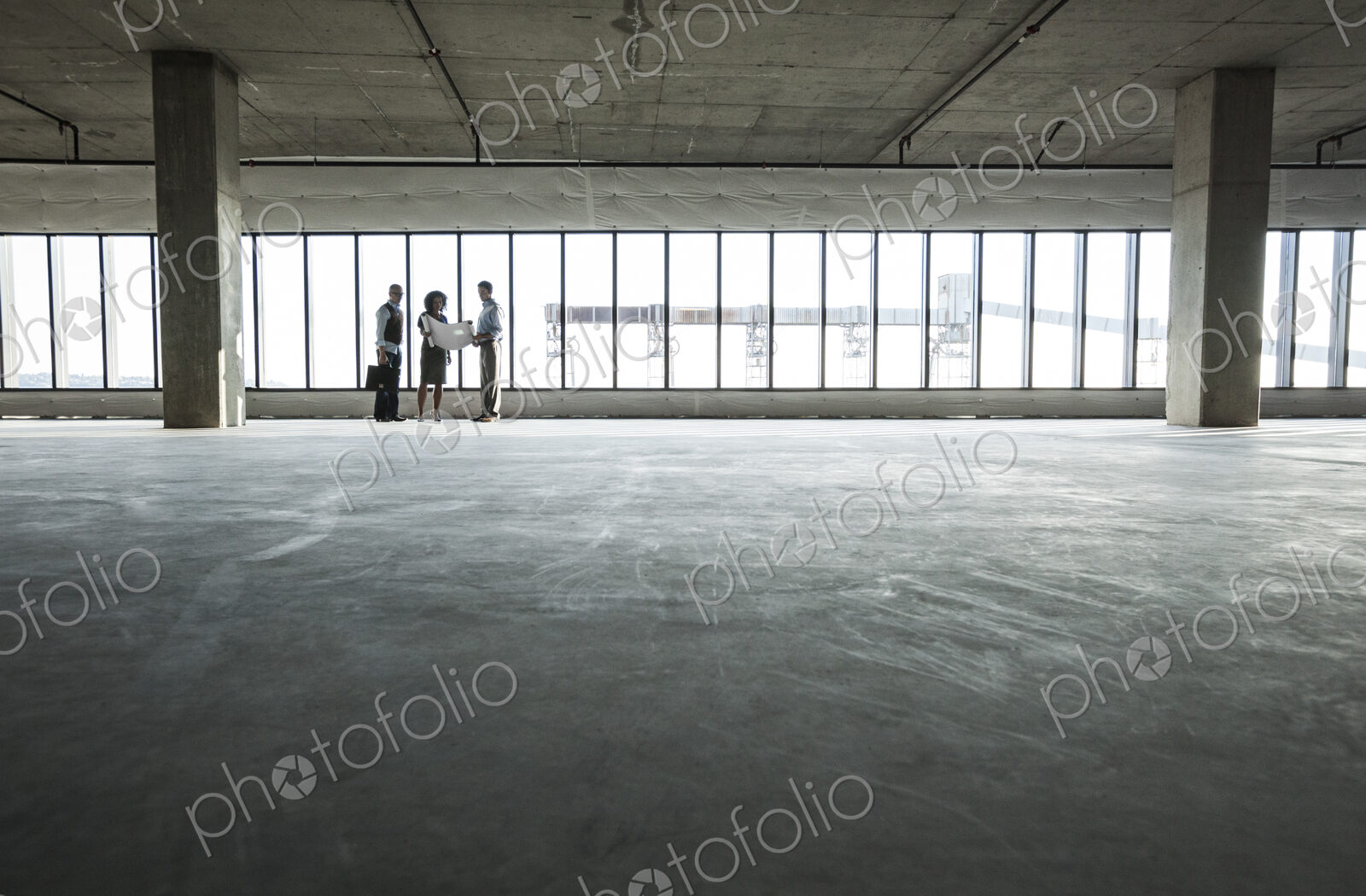 Group of business people looking at a new empty raw office space.