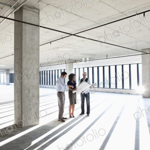 Group of business people looking at a new empty raw office space.