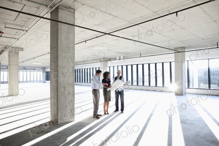 Group of business people looking at a new empty raw office space.