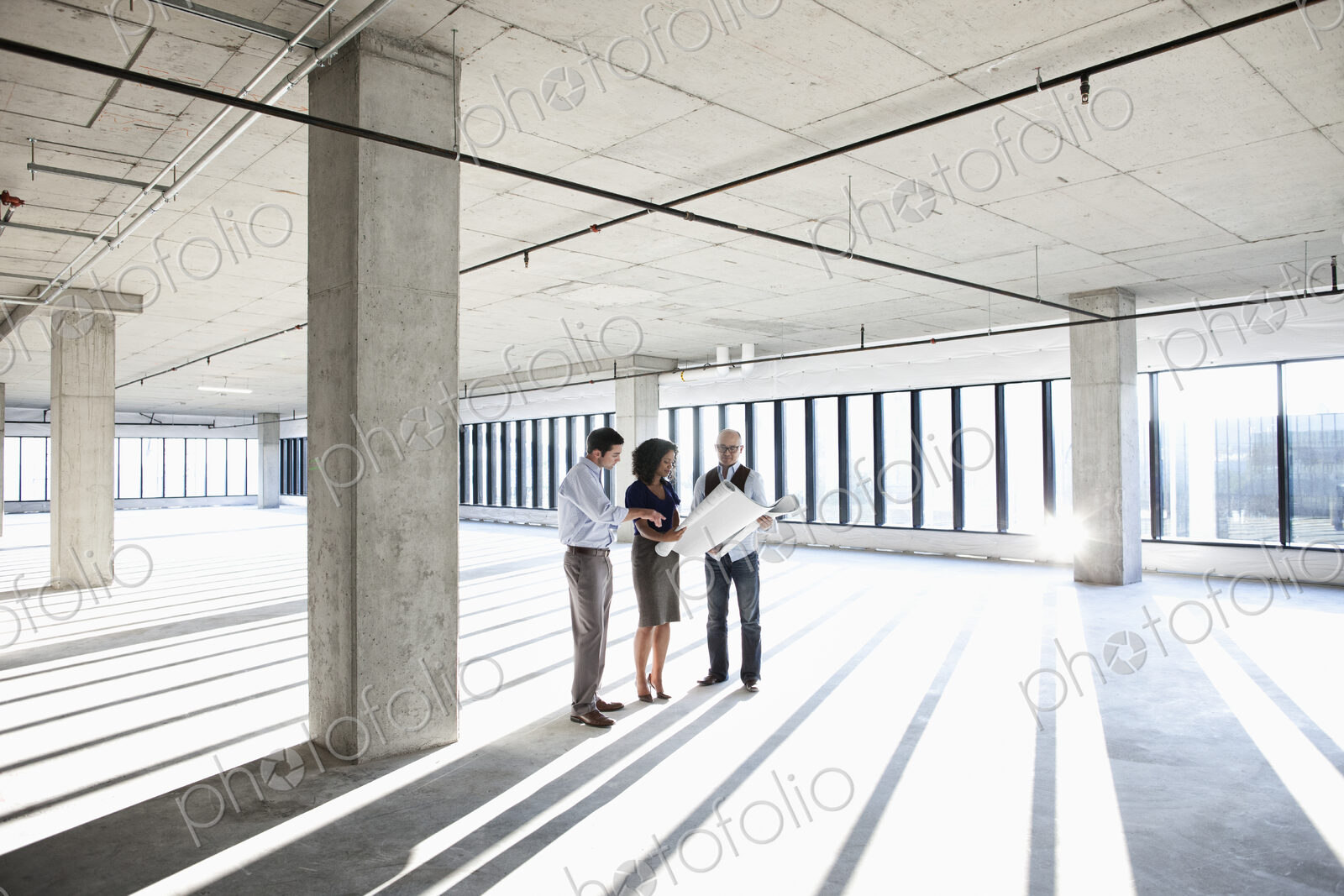 Group of business people looking at a new empty raw office space.
