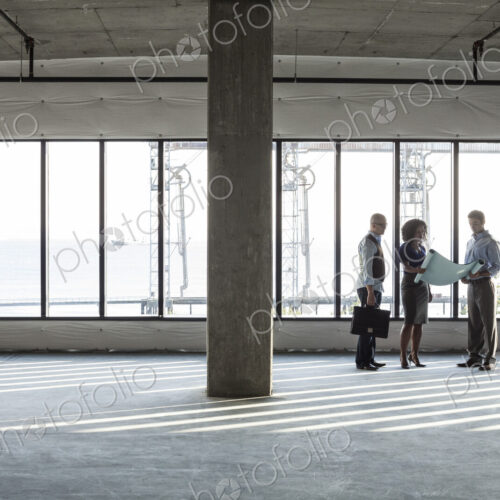 Group of business people looking at a new empty raw office space.