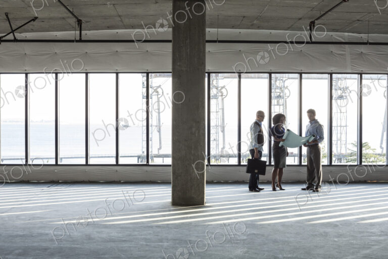 Group of business people looking at a new empty raw office space.