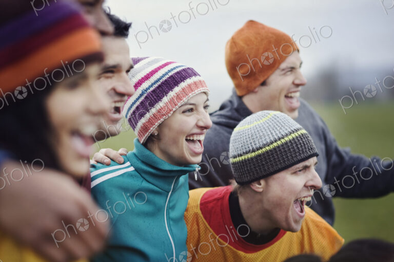 Group of men and women friends cheering at an informal sporting event in winter.