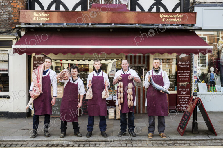 Group of men, butchers and fishmonger, wearing aprons, standing on the pavement…