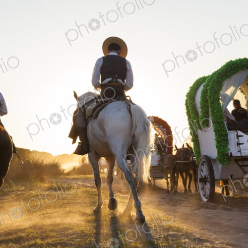 Group of people in horse-drawn wagons and on horseback on a rural dusty road. Group of people in horse-drawn wagons and on horseback on a rural dusty road.