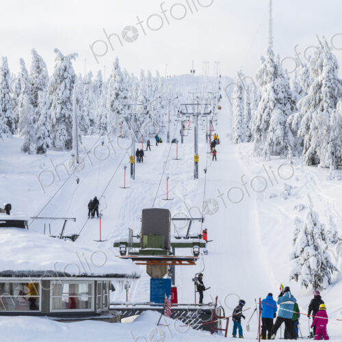 Group of people near a ski lift in forest with snow-covered trees. Group of people near a ski lift in forest with snow-covered trees.