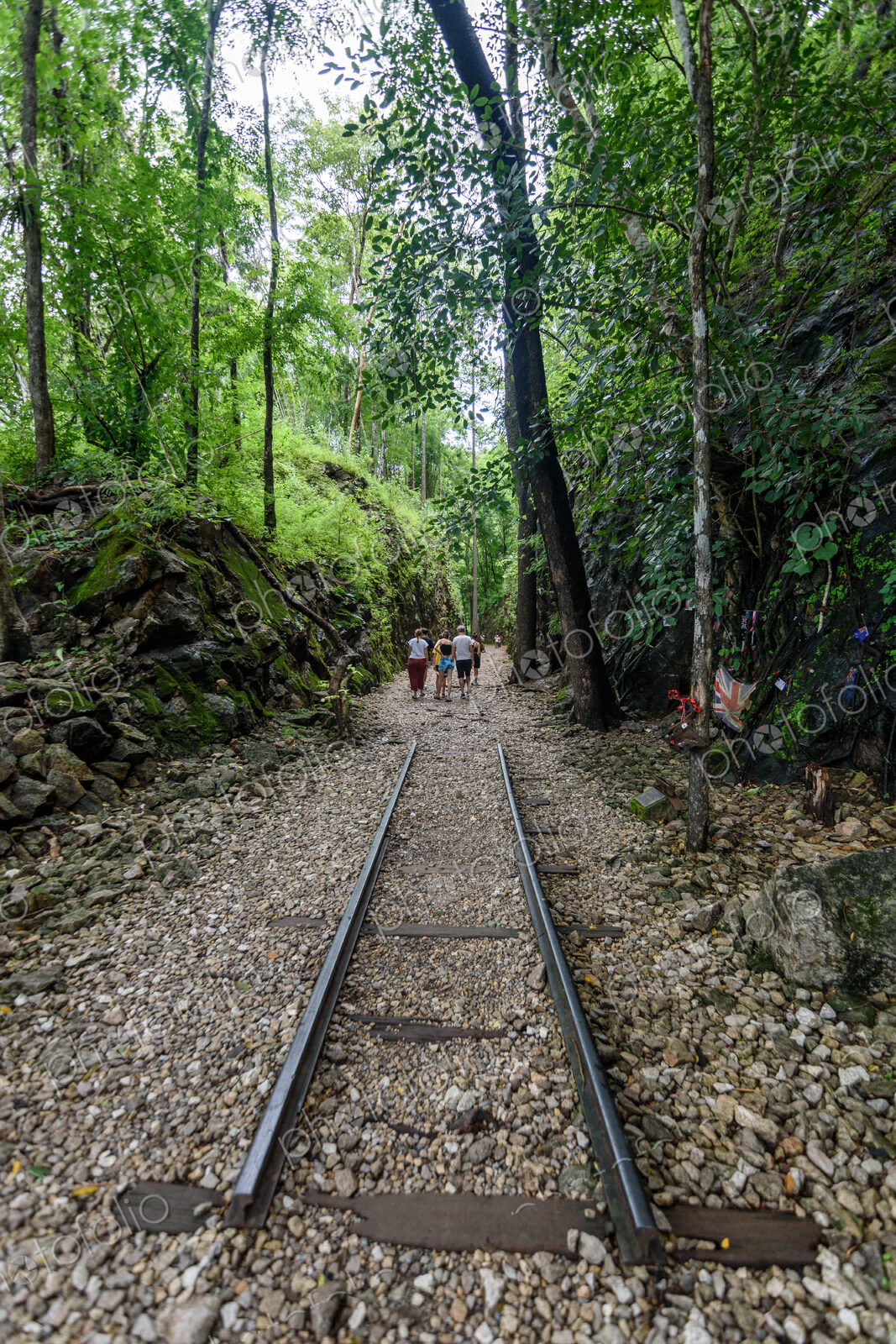 Group of people walking along railroad tracks in a forest in Bangkok.