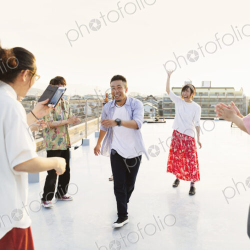 Group of young Japanese men and women dancing on a rooftop in an urban setting. Group of young Japanese men and women dancing on a rooftop in an urban setting.