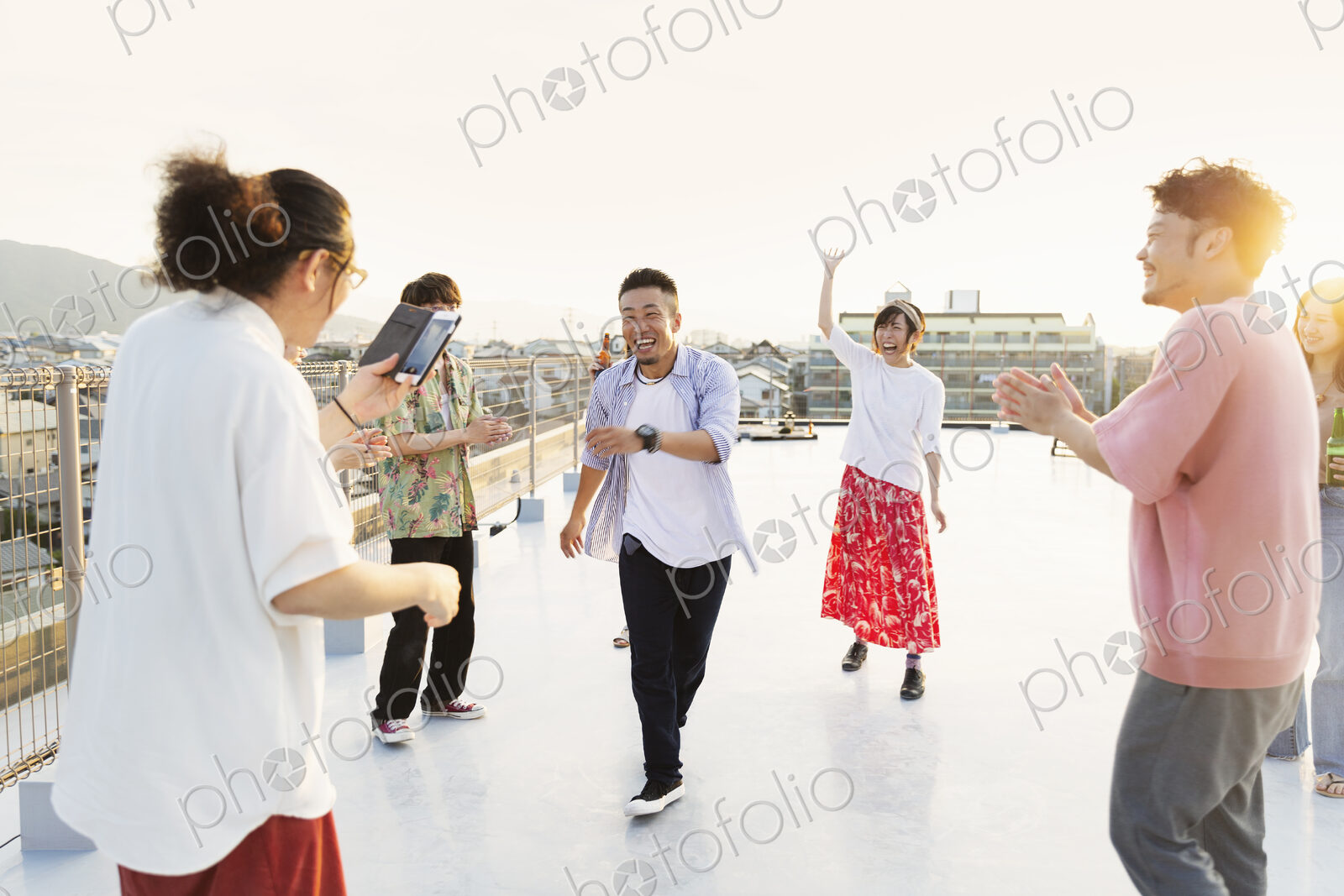 Group of young Japanese men and women dancing on a rooftop in an urban setting.